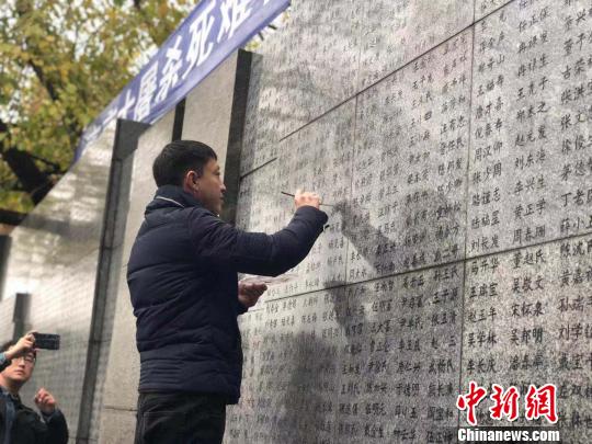 10日晨，下著小雨。南京大屠殺幸存者、死難者遺屬、學(xué)生們依次描寫(xiě)名字，祭悼南京大屠殺遇難同胞。淡淡的墨汁摻著雨水，滲入了刻在紀(jì)念館灰色厚重石壁上的黑色名字中?！≈鞎苑f 攝